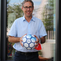 Michael Schrodi freut sich über den Fußball des Eine Welt Netzwerk Bayern